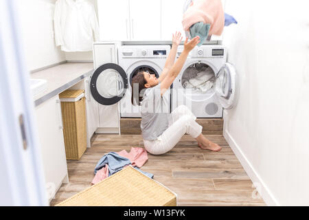 Happy family mother housewife in laundry room with washing machine throwing clothes up Stock Photo