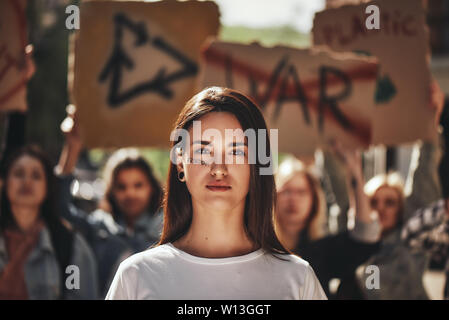 Female young activist with word freedom written on her face protesting outdoors with group of demonstrators. Human rights. Protest concept. Ecology concept. Group protesting Stock Photo