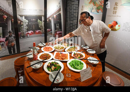 (190630) -- GUANGZHOU, June 30, 2019 (Xinhua) -- Su Yingchang, the inheritor of Guangzhou Dragon Boat intangible cultural heritage, introduces the meal for the Dragon Boat Festival in Chebei, Guangzhou, south China's Guangdong province, June 4, 2019. Chebei is an ancient village with a history of more than 1,000 years and over 200,000 permanent residents in Guangzhou, south China's Guangdong province. The Chebei Village Dragon Boat is listed as the intangible cultural heritage of Guangzhou. The Dragon Boat Festival consists of many key steps which has been preserved integrally.    On the eight Stock Photo