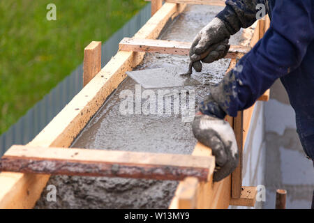 Worker levels concrete in formwork using a trowel Stock Photo