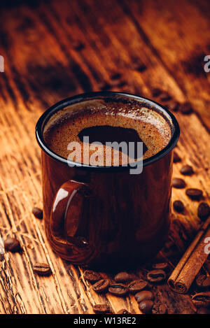 Brewed black coffee in metal mug over wooden surface Stock Photo