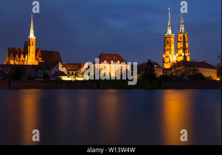 Night photography. View over the river Odra: Illuminated church, cathedral and buildings with reflections in the river. Wroclaw, Poland Stock Photo