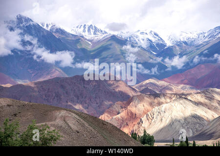 View of the colorful mountains and snow-capped peaks with clouds on them. Travel Kyrgyzstan. Stock Photo