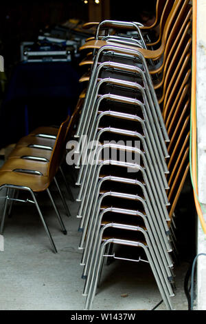 stacked metal chairs in a dark room Stock Photo