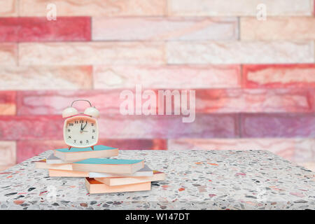 alarm clock and books on stone shelf in library school concept with brick wall blur background copy space add text Stock Photo