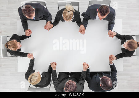 Business team holding hands sitting around the table, top view , copy space for text Stock Photo