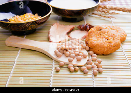 soy bean in wooden spoon and cereal cookies milk in bowl Cornflakes spices on wood bamboo. copy space for text. top view Stock Photo