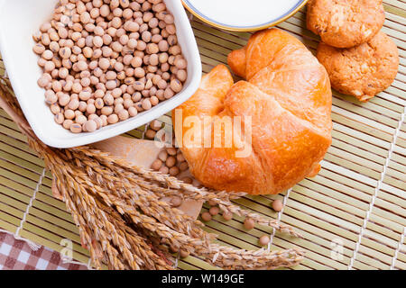 croissant baked bread with Milk in bowl soy bean in cup cookie and  spices on wooden bamboo. copy space for text. top view Stock Photo