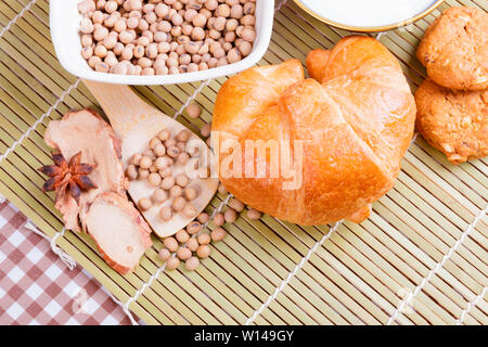 croissant baked bread with Milk in bowl soy bean in cup cookie and  spices on wooden bamboo. copy space for text. top view Stock Photo