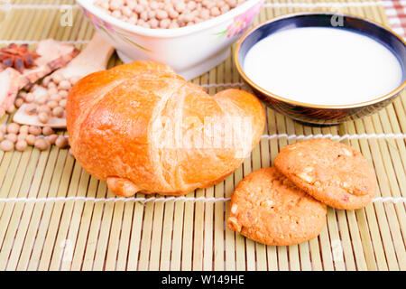 croissant baked bread with Milk in bowl soy bean in cup cookie and  spices on wooden bamboo. copy space for text. top view Stock Photo