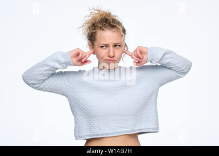 Beautiful curly young european woman plugging ears, looking aside Stock Photo