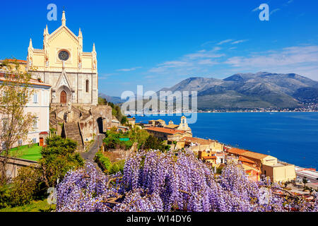 Gaeta, Italy, blooming wisteria flowers and historical churches of St Francis of Assisi and Santissima Annunziata over the blue waters of the bay of G Stock Photo