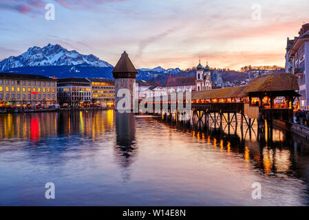 Lucerne, Switzerland, the wooden Chapel bridge in historical Old town and Mount Pilatus reflecting in Reuss river on dramatical sunset Stock Photo