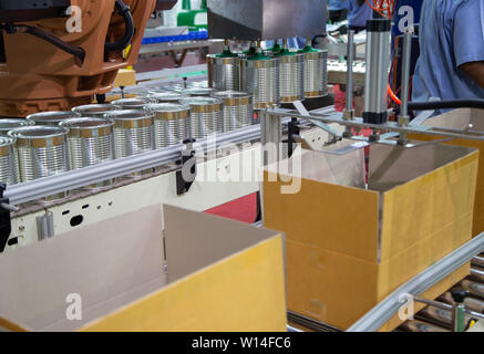 Automation robot lifting food can into cardboard in production line Stock Photo