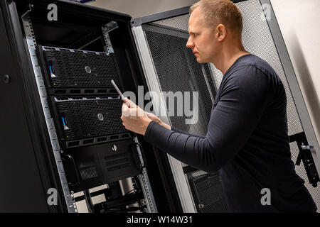 IT Support Holding Digital Tablet Analyzing Servers And Network In Datacenter Stock Photo