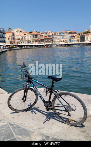 Chania, Crete, Greece. June 2019. A modern expenesive bicycle on a stand on the Old Venetian Harbour in Chania, Crete against a blue sky. Stock Photo