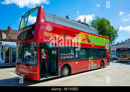 A bright red open topped  hop-on hop-off double decker bus which takes tourists on a tour around the City of York