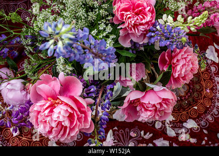 A bouquet of beautiful peonies and wild flowers is in a vase on a table Stock Photo