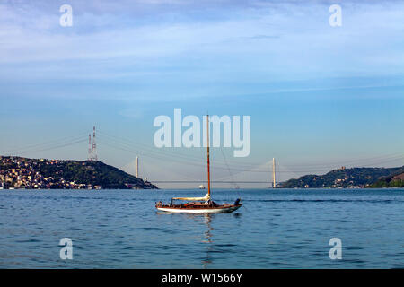a small white sailing boat is anchored on Marmara Sea. You can see 3rd Bosphorus (Yavuz Sultan Selim) Bridge from Sariyer coast, Istanbul, Turkey Stock Photo