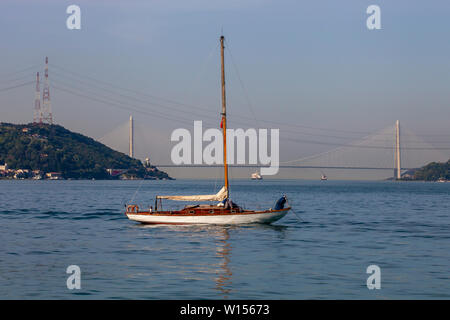 a small white sailing boat is anchored on Marmara Sea. You can see 3rd Bosphorus (Yavuz Sultan Selim) Bridge from Sariyer coast, Istanbul, Turkey Stock Photo