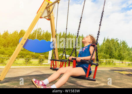 Little child blond girl having fun on a swing Stock Photo