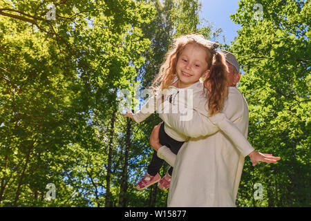 Father holding on hands daughter and show a flying plane. Stock Photo