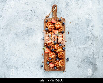 Small round delicious soft belgian waffles on cutting board. Fresh belgian waffles with berries and caramel sauce top view. Copy space for text or mock up Stock Photo