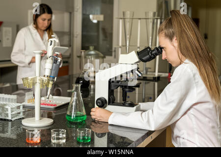 Team of two, Caucasian white, female laboratory technicians in white robes working in chemical or pharmaceutical laboratory, laboratory equipment and Stock Photo