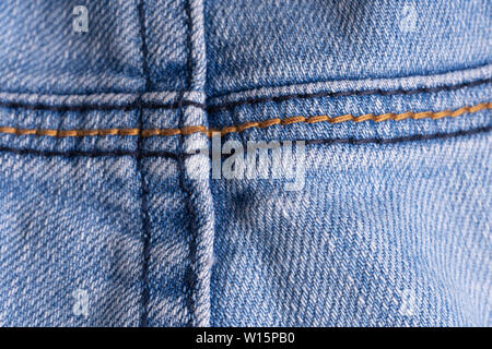 Blue denim. Cotton fabric, jeans. Creative vintage background. Pocket and zipper. The line is of poor quality. Cheap item Stock Photo