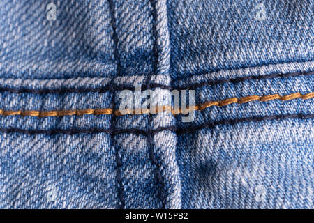 Blue denim. Cotton fabric, jeans. Creative vintage background. Pocket and zipper. The line is of poor quality. Cheap item Stock Photo