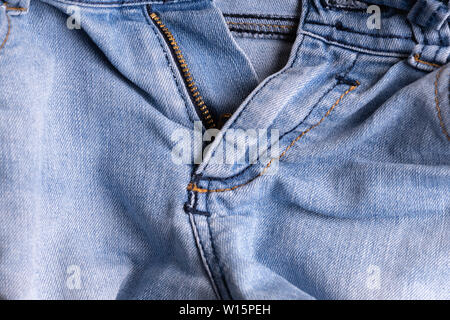 Blue denim. Cotton fabric, jeans. Creative vintage background. Pocket and zipper. The line is of poor quality. Cheap item Stock Photo