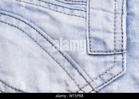 Blue denim. Cotton fabric, jeans. Creative vintage background. Pocket and zipper. The line is of poor quality. Cheap item Stock Photo