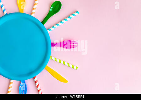 Top view of multicolored tableware and drinking straws abstract isolated on pastel rose. Space for copy. Stock Photo