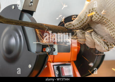 Master sharpens on the machine metal knife lawn mower. The master's hand in white gloves holding metal plate. Stock Photo