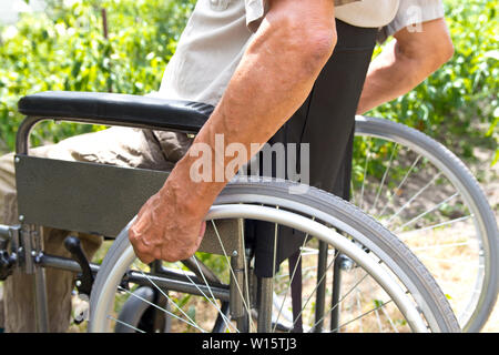 A disabled man is sitting in a wheelchair ,   Holds his hands on the wheel. Handicap people Concept     . Stock Photo