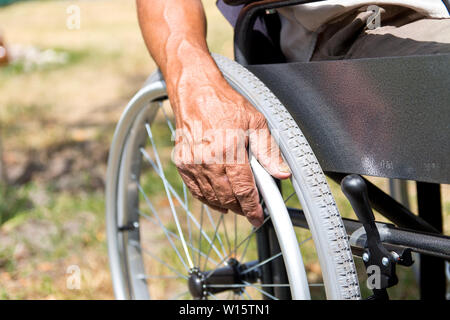 A disabled man is sitting in a wheelchair ,   Holds his hands on the wheel. Handicap people Concept     . Stock Photo