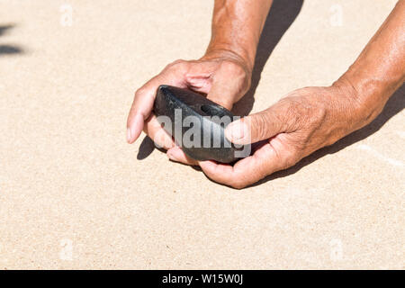An old stone Hammer an elder man holds in his hands. Archaeology. Study of ancient objects Stock Photo