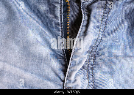 Blue denim. Cotton fabric, jeans. Creative vintage background. Pocket and zipper. The line is of poor quality. Cheap item Stock Photo