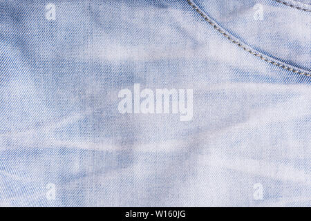 Blue denim. Cotton fabric, jeans. Creative vintage background. Pocket and zipper. The line is of poor quality. Cheap item Stock Photo