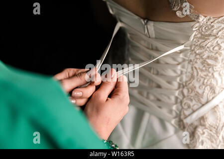 Bride from the back. Lacing the wedding dress Stock Photo - Alamy