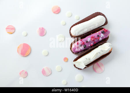 A set of three eclairs with different fillings and design isolate on a white surface decorated with drops of white chocolate, copyspace Stock Photo