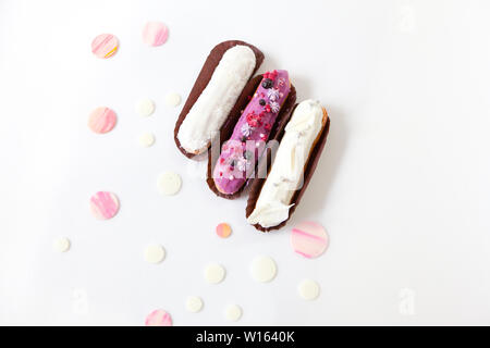 A set of three eclairs with different fillings and design isolate on a white surface decorated with drops of white chocolate, copyspace Stock Photo
