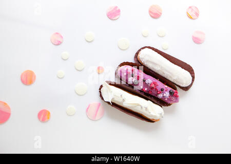 A set of three eclairs with different fillings and design isolate on a white surface decorated with drops of white chocolate, copyspace Stock Photo