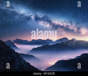 Milky Way over mountains in fog at night in summer Stock Photo