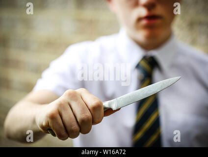 Teenage school boy holding a knife to illustrate knife crime in uk schools Stock Photo