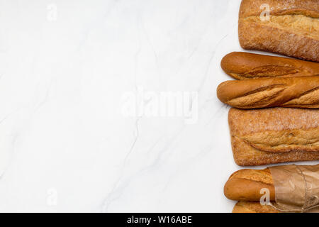 Different kind of breads on white marble background. Top view, horizontal right edge banner. Copy space for text Stock Photo