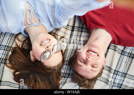 Top view portrait of young couple lying on picnic blanket and smiling happily at camera, copy space Stock Photo