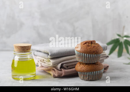 Different products from marijuana. Baking muffins from cannabis, natural CDB fabric and oil. Gray background Stock Photo