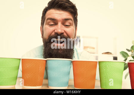 Alternative concept. Pick one. Diversity and recycling. Eco paper cup. Coffee to go paper cup. How many cups per day. Choose from alternatives. Man bearded choosing one of lot colorful paper cups. Stock Photo