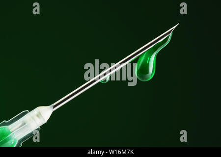 Syringe filled with green drug and dripping from the needle Stock Photo